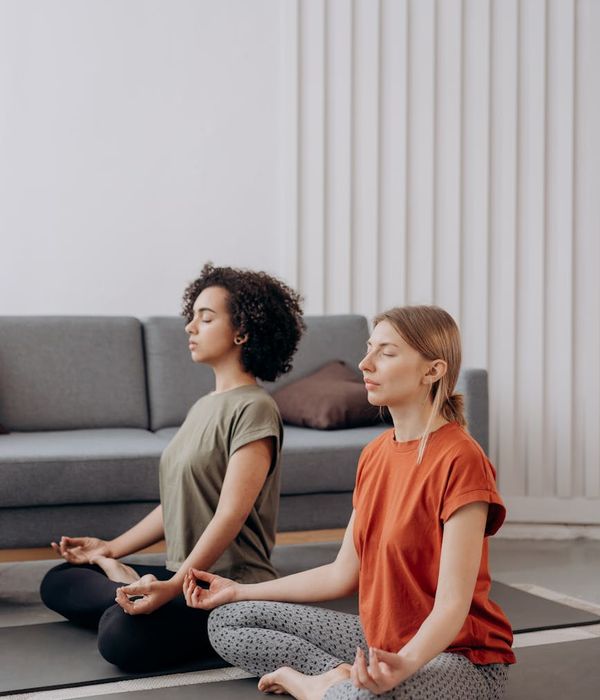 Woman in a calm, seated yoga pose in a bright, minimalist room.